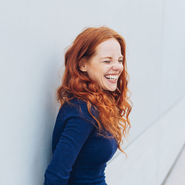 woman laughing while leaning against a wall