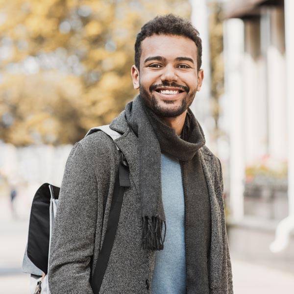 man smiling and carrying a backpack