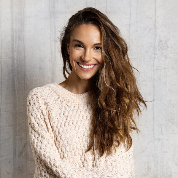 woman smiling and leaning against a wall